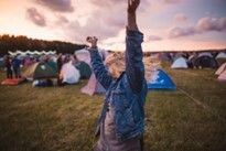 Festival goer dancing in front of some tents at sunset