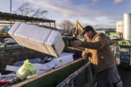 Man putting recycling in a container at a recycling centre