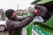 Man putting recycling in a container at a recycling centre