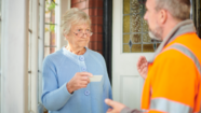 Elderly woman looking unhappily at the business card of an uninvited door to door caller