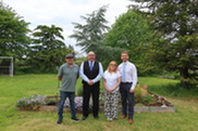 Councillors with foster carers Dawn and Lee outside in a green garden surrounded by trees.
