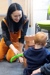 Little Creatives artist playing with a child in a library.