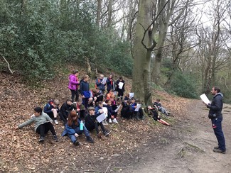 Class of school children await instructions from their teacher in a woodland