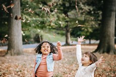 Child stands in a shower of leaves