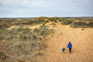 Family walking through sand dunes at Kenfig National Nature Reserve