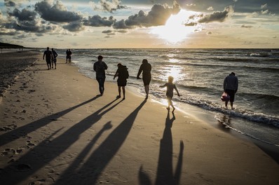 A family take a walk along a beach at sunset