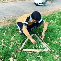 Using branches to make a triangle, learners fills it with natural items