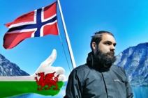 Man stands by Norweigen fjord with Norway and WElsh flags on show