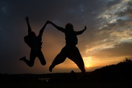 Two people jump in the sky at daybreak