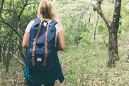 A teenager walks with her back to the camera in a forest