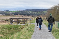 A man and two children walk the Wales Coast Path at Talacre