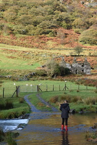 A child walks in a river wearing wellies