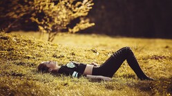 A girl lies on her back in the grass looking up