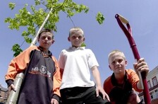 Three boys with spades looking down at camera in urban setting