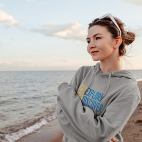Woman wearing a grey hoodie at the coast