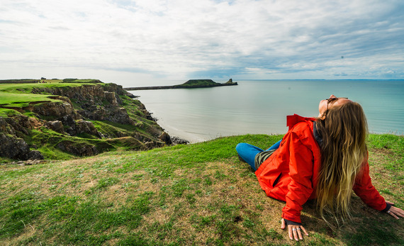 woman sitting on grass looking out to sea