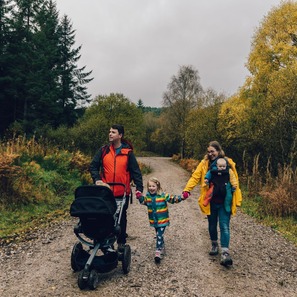 A young family with a pushchair take a walk through an autumnal woodland