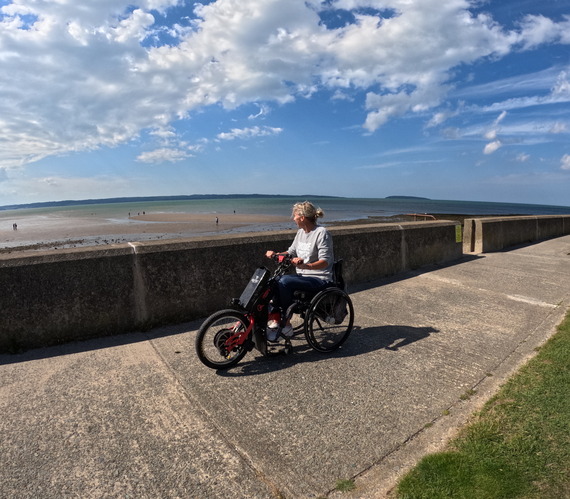 woman in her wheelchair on a promenade looking out to sea