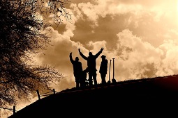 People planting a tree at the top of a hill - silhouette