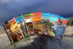 Wales Coast Path guidebooks in a row on a coastal background