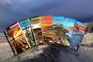 Wales Coast Path guidebooks in a row on a coastal background