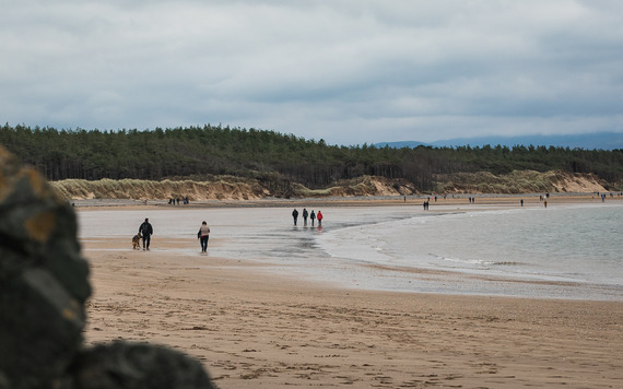 people walking on the beach with the tide in