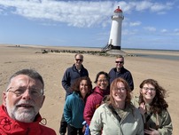 people on a beach and a lighthouse in the background