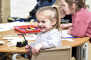 Young girl at a table with other children with colouring pencils