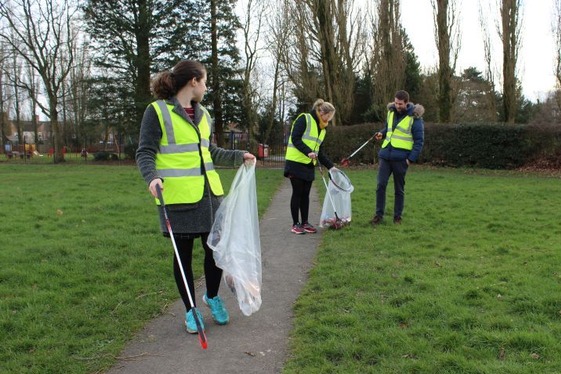 Three people litter picking in a park
