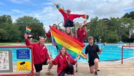 Pride Paddle and Picnic. Image of lifeguards holding rainbow Pride flags. 