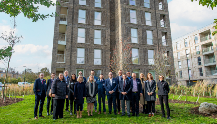 Image of teams from OCC and Peabody stand in front of a new block of flats 