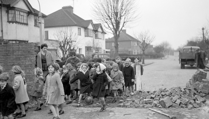 Black and white image of young children walking through a demolished section of wall in 1959. Credit to Oxfordshire History Centre 