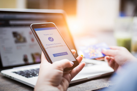 Image representing digital economy, someone on a laptop also using a phone and with a credit card for shopping