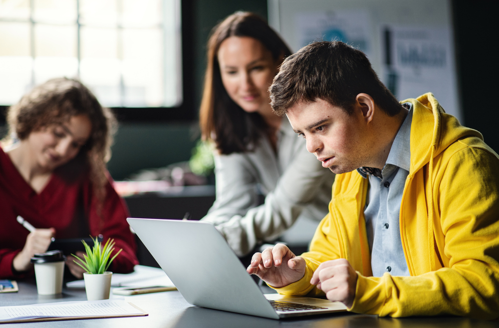 Two adults helping a child on a laptop