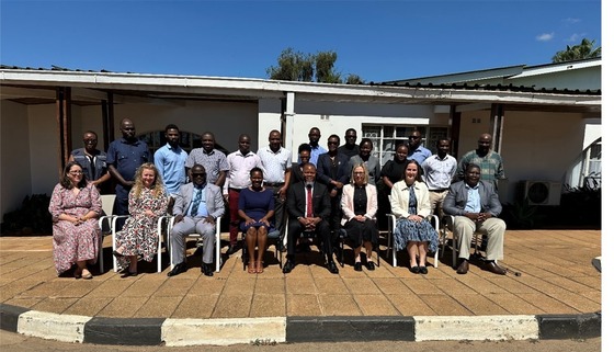 People sat in chairs in from of low building near a kerb