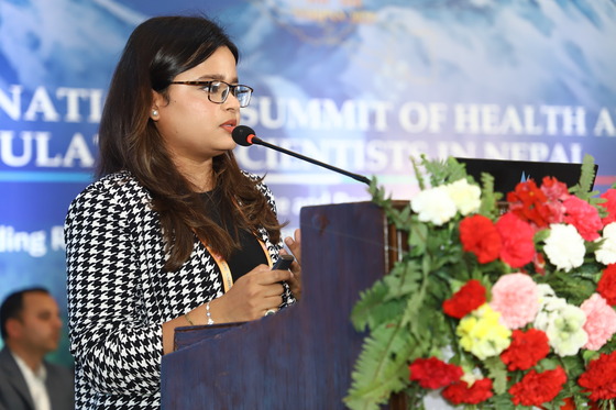 woman standing at a lecturn speaking into a mic
