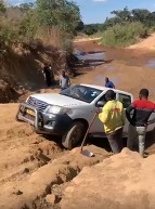 Jeep in sand with people nearby