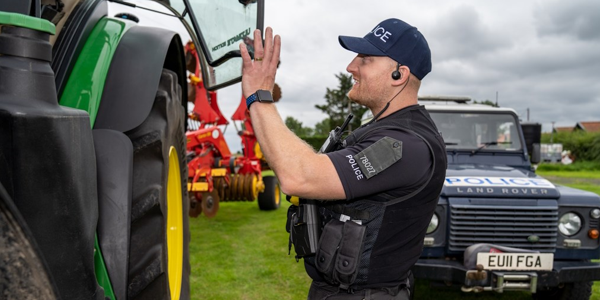 Police officer talking to a person out of shot in a tractor with a police vehicle in the background