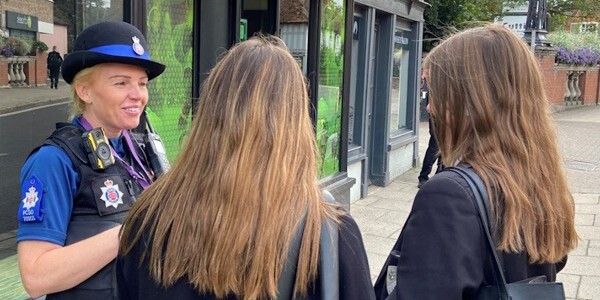 A police community support officer speaks to two students