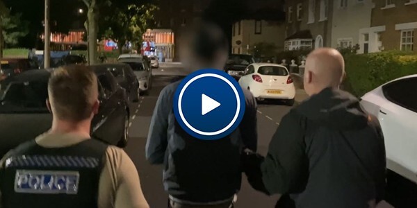 Plain clothes police officers accompany a male suspect at night in a street