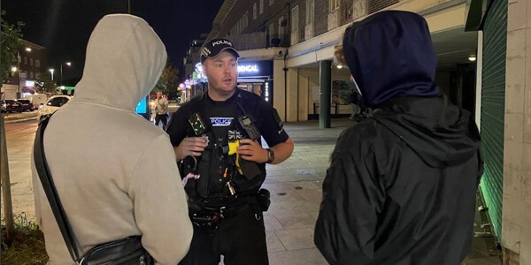 An officer talking to two people with their backs turned in Debden.
