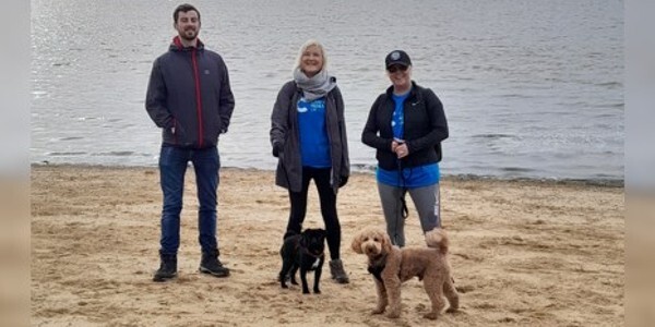 Three people and two dogs on a beach