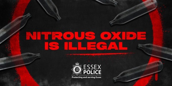 Text: Nitrous Oxide is illegal in red on a black background with a red circle and dark nitrous oxide cannisters scattered around.