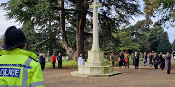 Officer at the war memorial with others who are laying poppy wreaths