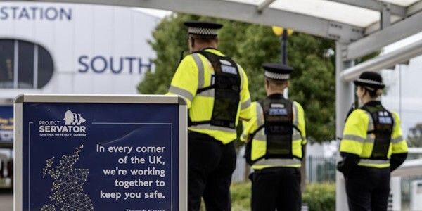 Three officers on patrol with a Project Servator sign in the foreground