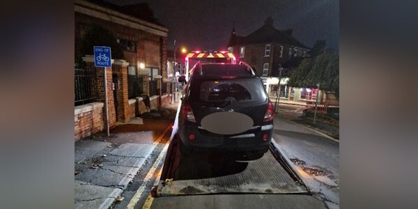 Black car on the back of a transporter lorry at night