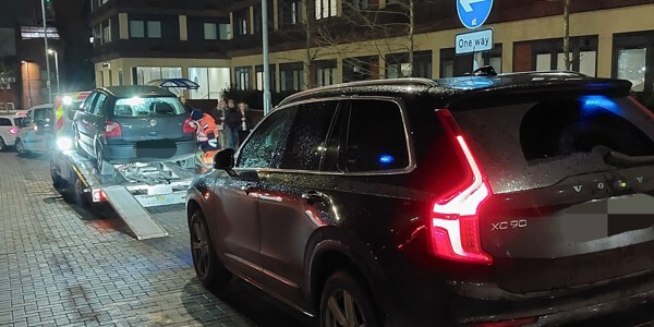 Cars being loaded onto transporter at night in a one way street