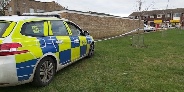 Police car and police tape at scene cordon near shops in Allecutus Way, Witham