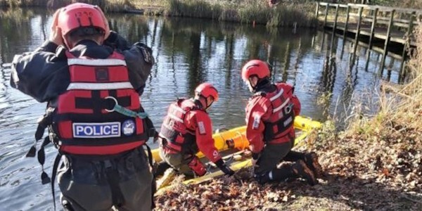 Police divers next to Oakwood Pond with boat