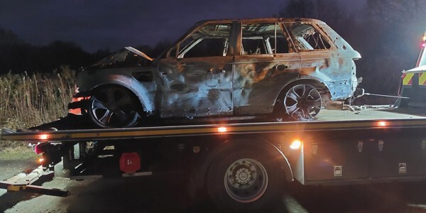 Burned car on the back of a recovery vehicle at night